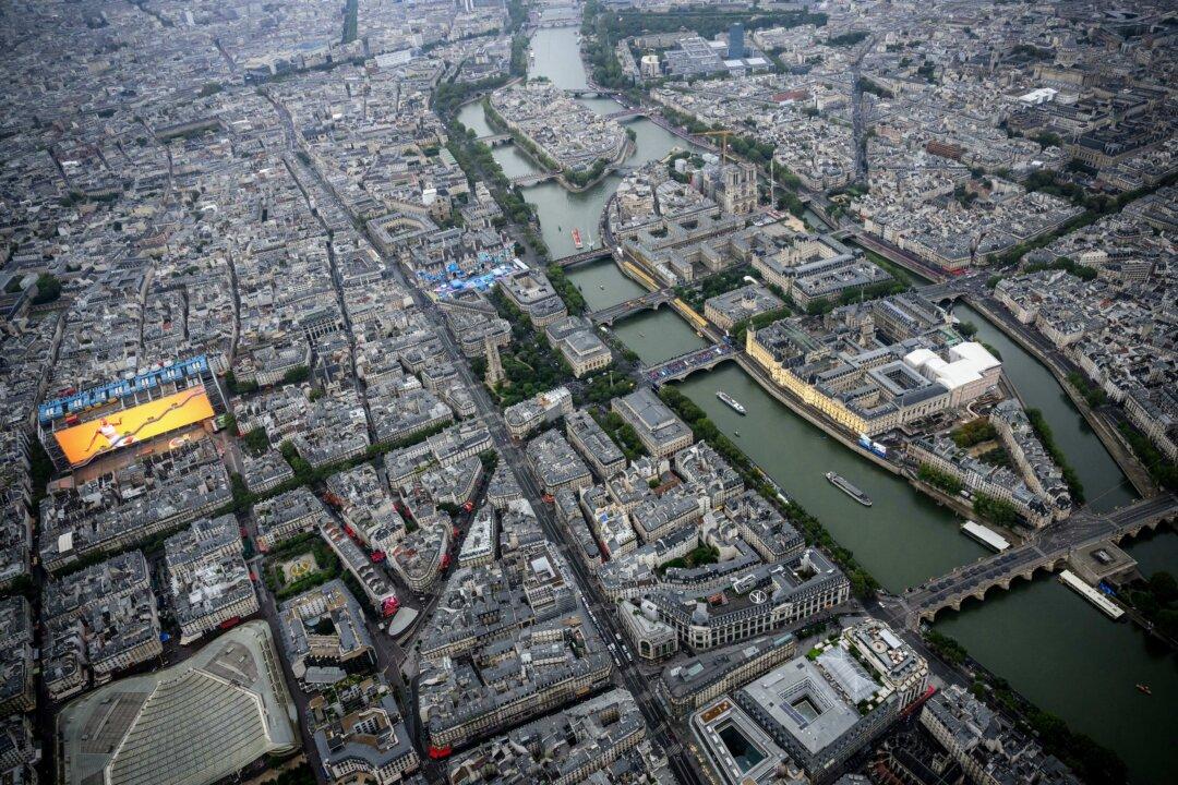 An aerial view of Notre-Dame de Paris Cathedral as delegations boats navigates on the Seine past the Ile de la Cite Island (front R), Saint-Louis Island (rear R) and Centre Pompidou museum (L) during the opening ceremony of the Paris 2024 Olympic Games in Paris on July 26, 2024. (Lionel Bonaventure/Pool/AFP via Getty Images)