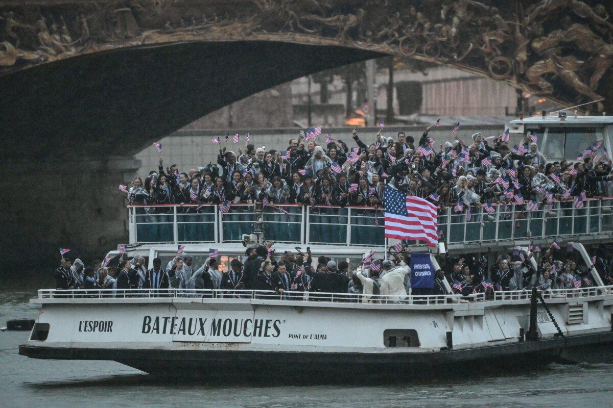 Athletes from the U.S. delegation wave flags as they sail on a boat along the river Seine during the opening ceremony of the Paris 2024 Olympic Games in Paris on July 26, 2024. (Miguel Medina/AFP via Getty Images)