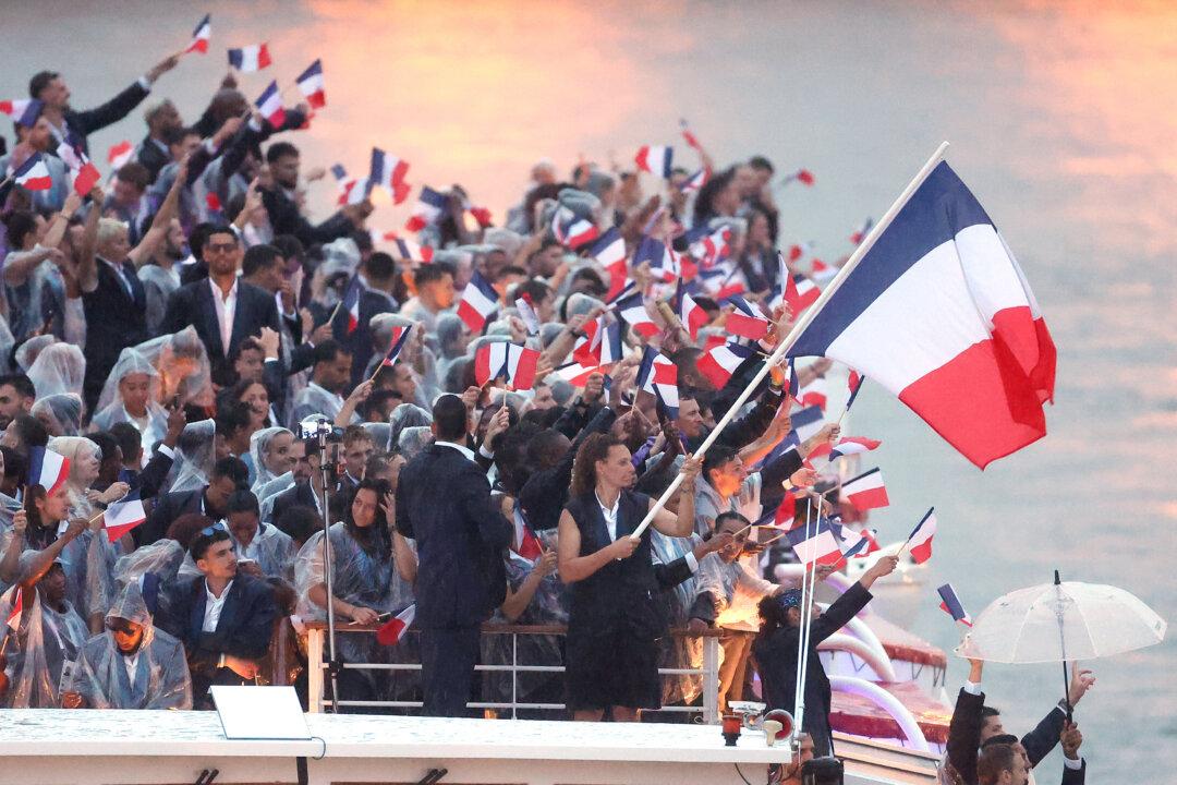 Florent Manaudou and Melina Robert-Michon, Flagbearers of Team France, wave their flag on a boat with team mates along the River Seine during the opening ceremony of the Olympic Games Paris 2024 in Paris on July 26, 2024. (Alex Pantling/Getty Images)