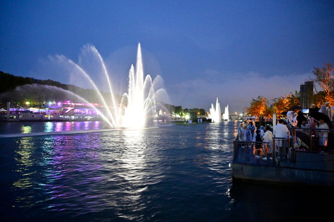 Spectators watch a light and water show from the banks of the river Seine during the opening ceremony of the Paris 2024 Olympic Games in Paris, on July 26, 2024. (John Macdougall/Pool/AFP)