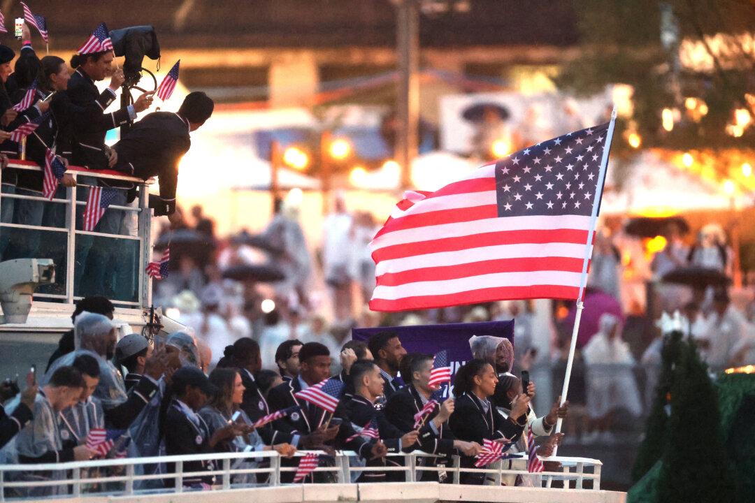 Lebron James, flagbearer of Team United States, holds the U.S. flag on a boat with team mates along the River Seine during the opening ceremony of the Olympic Games in Paris, on July 26, 2024. (Steph Chambers/Pool/AFP via Getty Images)