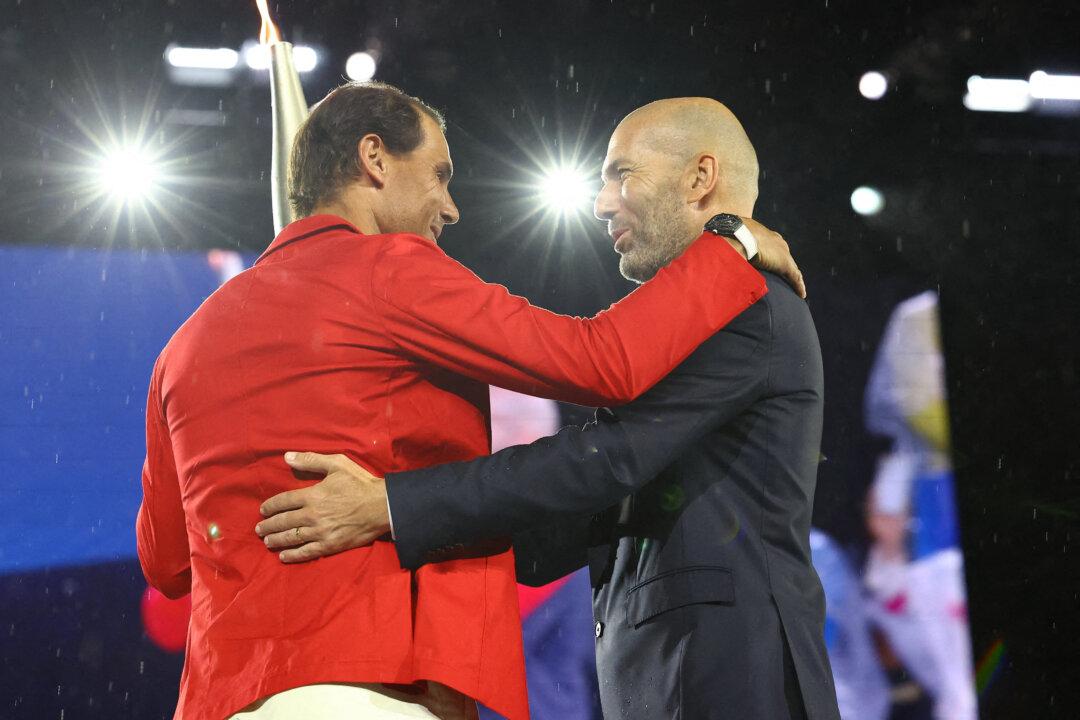 Torchbearer Zinedine Zidane passes the Olympic torch to Rafael Nadal of Spain during the Olympics Opening Ceremony in Paris on July 26, 2024. (Stephanie Lecocq /Pool/AFP via Getty Images)