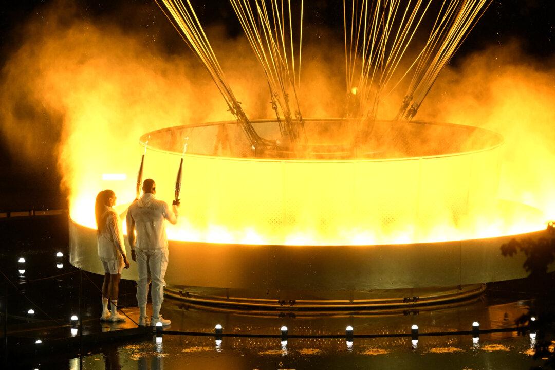 Torchbearers Teddy Riner (R) and Marie-Jose Perec light up the Olympic cauldron during the opening ceremony of the Paris 2024 Olympic Games in Paris, France, on July 26, 2024. (Xia Yifang-Pool/Getty Images)