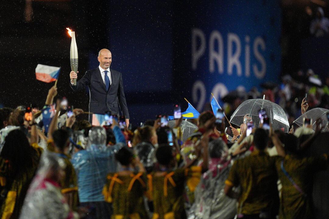 Former French football player Zinedine Zidane holds the Olympic torch during the opening ceremony of the Paris 2024 Olympic Games in Paris, France, on July 26, 2024. (Xu Chang-Pool/Getty Images)