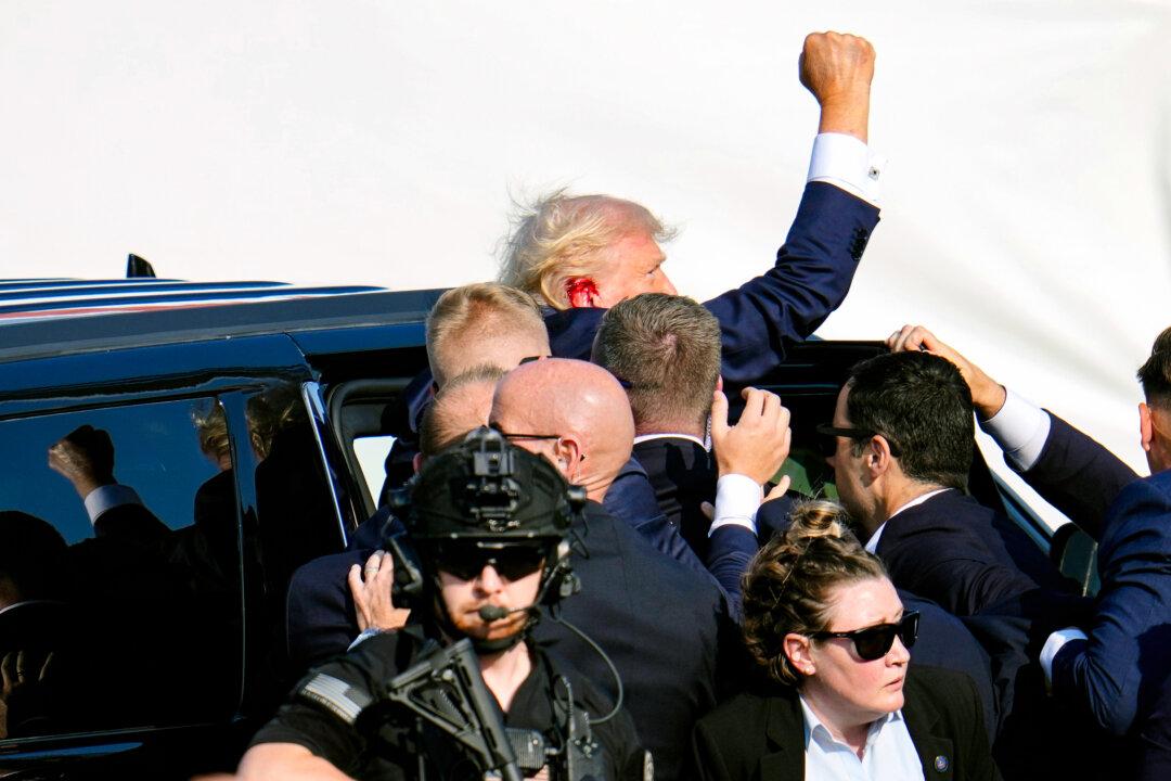 Former President Donald Trump pumps his fist as he is helped into a vehicle to leave the rally. (Gene J. Puskar/AP Photo)