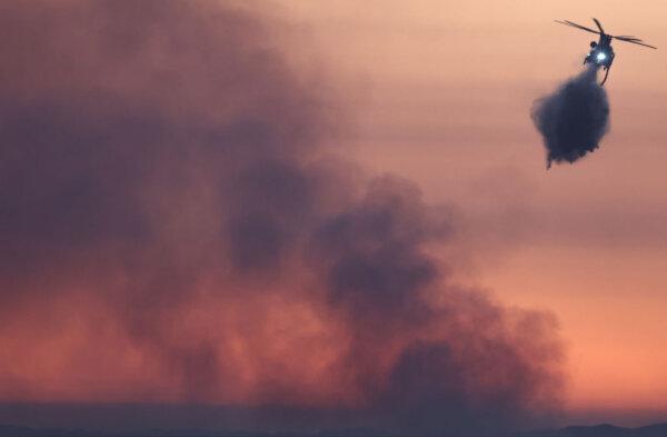 A firefighting helicopter drops water as the Nixon Fire burns with evacuation orders in the area, near Aguanga of Riverside County, Calif., on July 29, 2024. (Mario Tama/Getty Images)