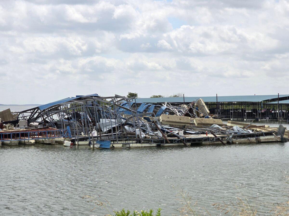 A wide-angle view of the debris pile where a powerful tornado plowed through Lake Ray Roberts Marina in Sanger, Texas, on May 25, 2024. Photos taken on July 29, 2024. (Below) Marina owner Bill Williams shows images of the damage to a trailer park at the marina. (Allan Stein/The Epoch Times)