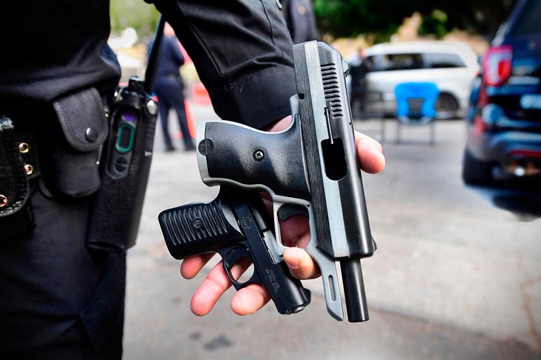 A Los Angeles Police Department officer shows recovered guns from residents turning in firearms at a Gun Buy Back event in Los Angeles on Dec. 5, 2020. (Frederic J. Brown/AFP via Getty Images)