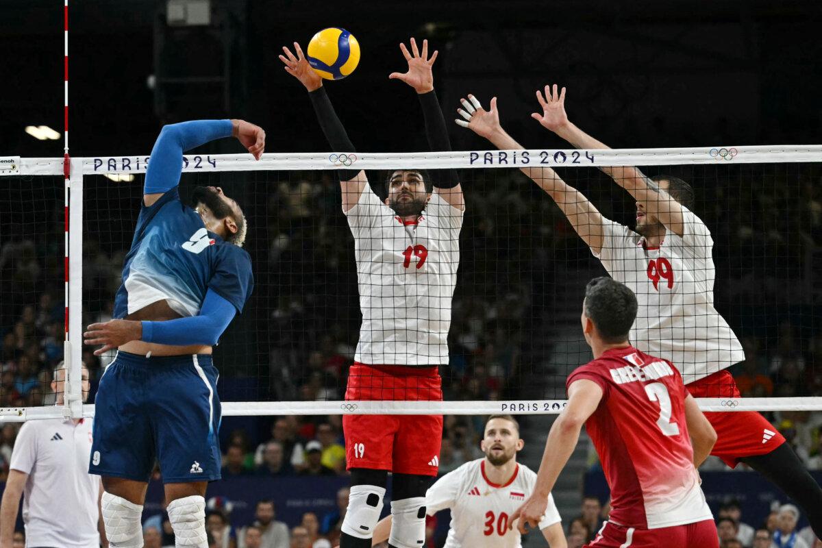 France's Earvin Ngapeth (9) passes the ball over the net in front of Poland's Marcin Janusz (19) and Poland's (99) Norbert Huber in the men's volleyball gold medal match between France and Poland at the South Paris Arena 1 in Paris during the Olympic Games on Aug. 10, 2024. (Mauro Pimentel /AFP via Getty Images)