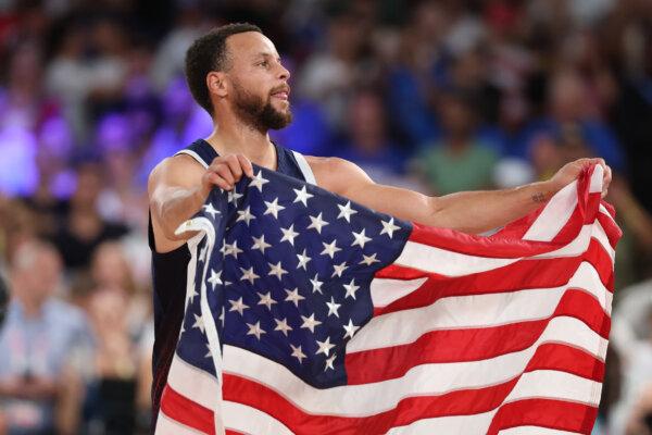 Stephen Curry (4) of Team United States celebrates with the American Flag after his team's victory against Team France during the Men's Gold Medal game between Team France and Team United States on day fifteen of the Olympic Games Paris 2024 at Bercy Arena in Paris, France, on Aug. 10, 2024. (Michael Reaves/Getty Images)