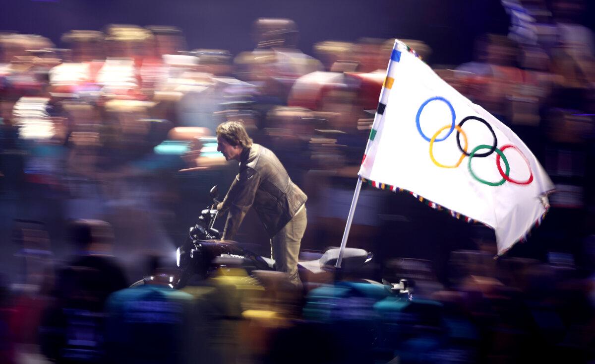 American Actor and film producer Tom Cruise rides on a motorbike with the IOC flag during the closing ceremony of the Olympic Games Paris 2024 at Stade de France in Paris, France, on Aug. 11, 2024. (Steph Chambers/Getty Images)