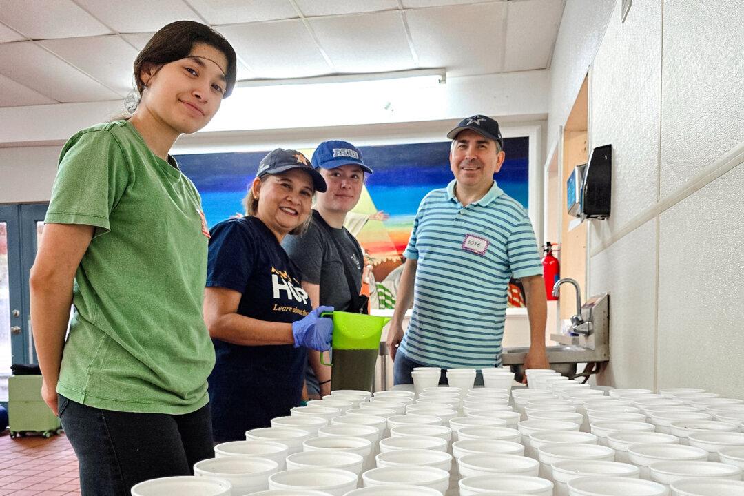 Volunteers line up cups filled with apple juice at Loaves &amp; Fishes Soup Kitchen in Houston on July 27, 2024. (Allan Stein/The Epoch Times)