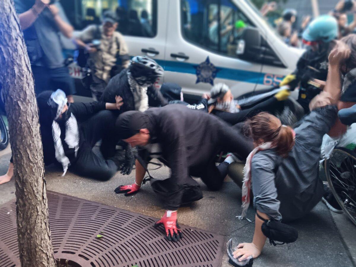 A protester is toppled as police and demonstrators clash near the Israeli consulate in Chicago with the Democratic National Convention happening nearby on Aug. 20, 2024. (Nathan Worcester/The Epoch Times).