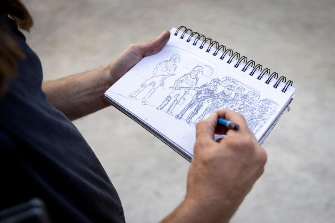 Artist Ike creates a drawing during protests for Gaza ceasefires during the 2024 DNC in Chicago on Aug. 22, 2024. (John Fredricks/The Epoch Times)