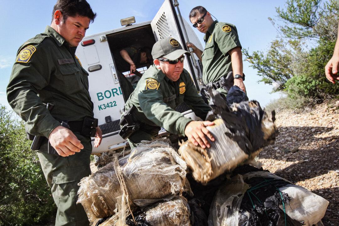 U.S. Border Patrol agents stack more than 400 pounds of marijuana seized from drug smugglers after it was brought across the Rio Grande from Mexico into the United States, near Laredo, Texas, on Aug. 7, 2008. (John Moore/Getty Images)