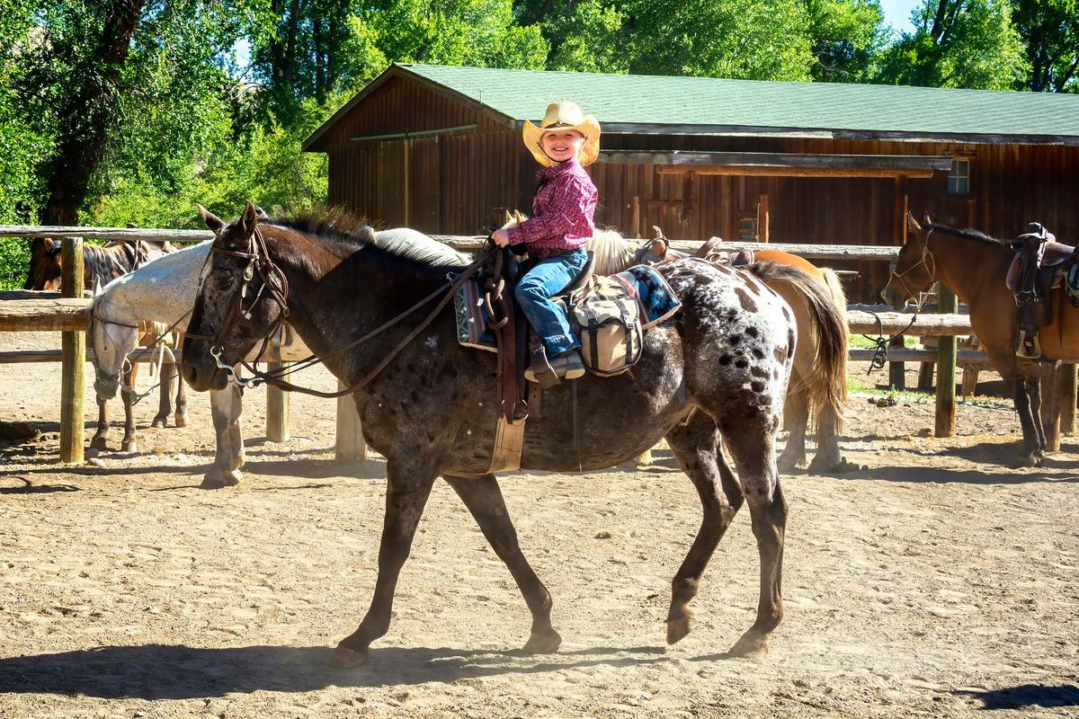 Saddled up and heading out of the main coral, five-year-old Charlie Pleasants flashes a brilliant cowgirl smile. (Maria Coulson)