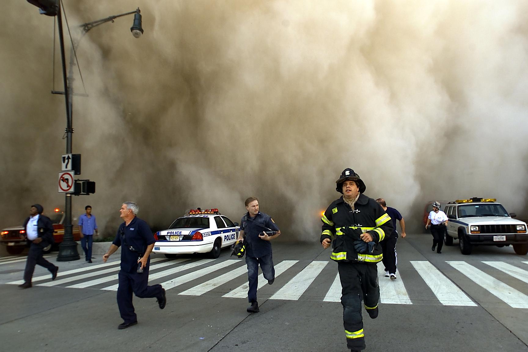 Policemen and firemen run away from the huge dust cloud caused by the World Trade Center's Tower One collapse after terrorists crashed two planes into the twin towers on Sept. 11, 2001, in New York City. (Jose Jimenez/Primera Hora/Getty Images)