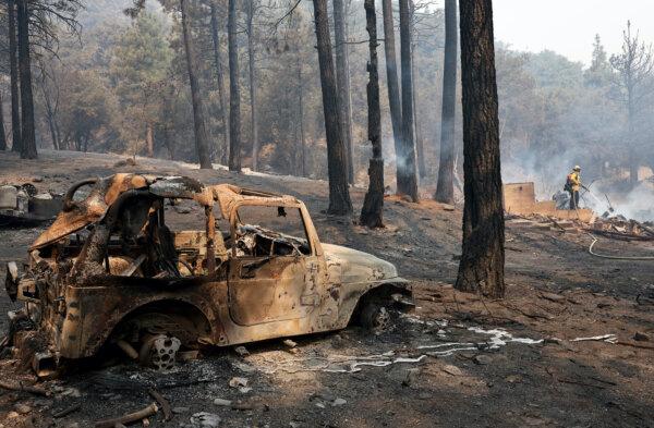 A firefighter sprays down the remnants of a destroyed home during the Bridge Fire in Angeles National Forest in Wrightwood, Calif., on Sept. 11, 2024. (Mario Tama/Getty Images)