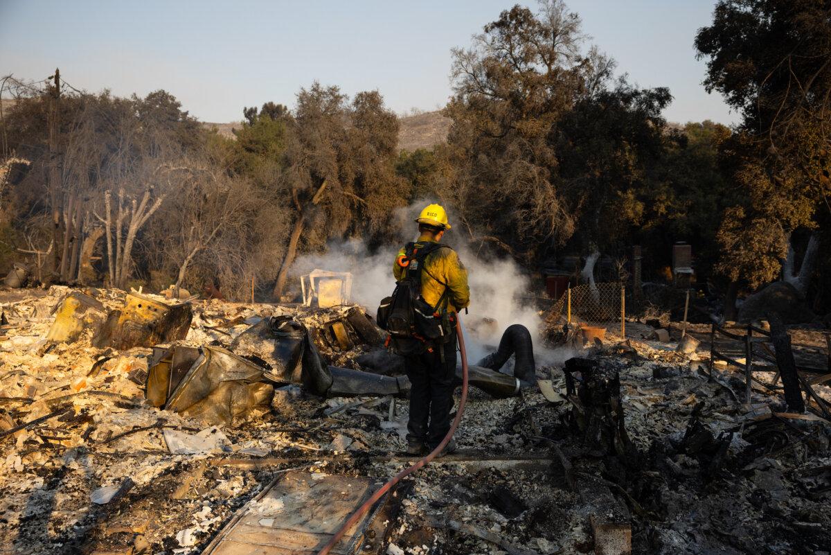 A firefighter from the Riverside County Fire Department puts out a hot spot in a home that burned in the Airport fire in El Cariso Village near Lake Elsinore, Calif., on Sept. 11, 2024. {Zoë Meyers/AFP via Getty Images)