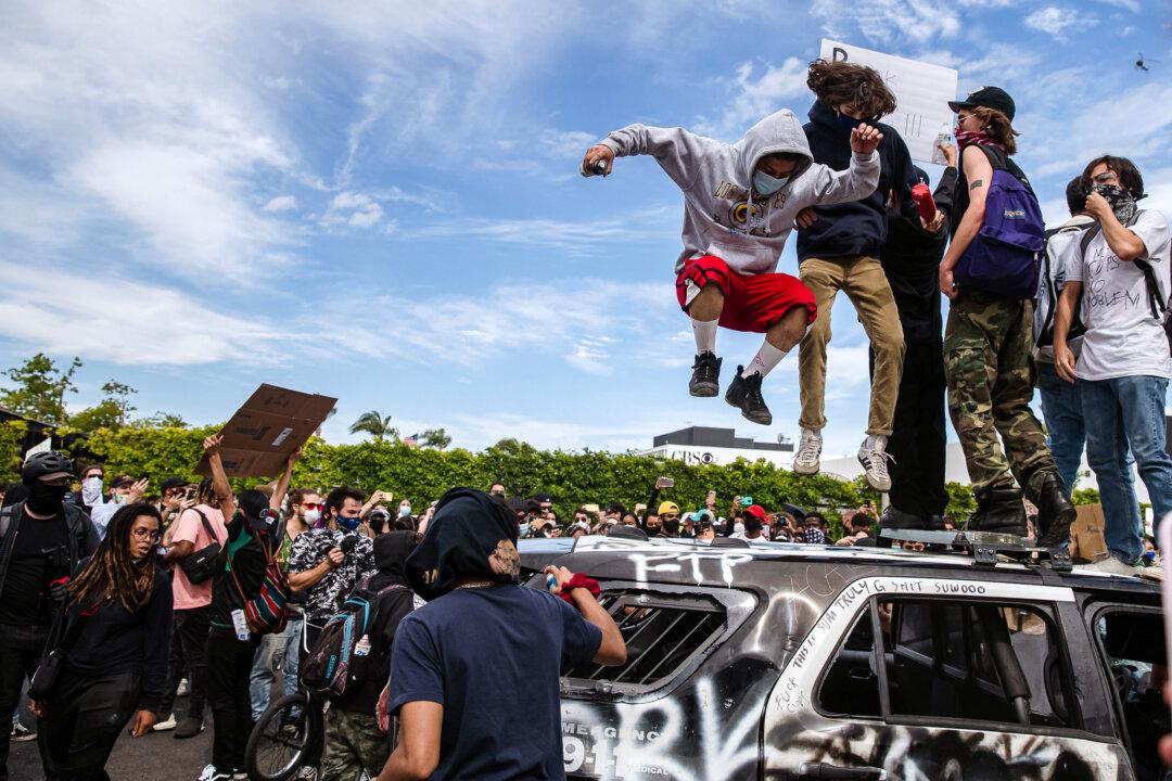 Demonstrators jump on a damaged police vehicle during a protest in Los Angeles on May 30, 2020. (Ariana Drehsler/AFP via Getty Images)