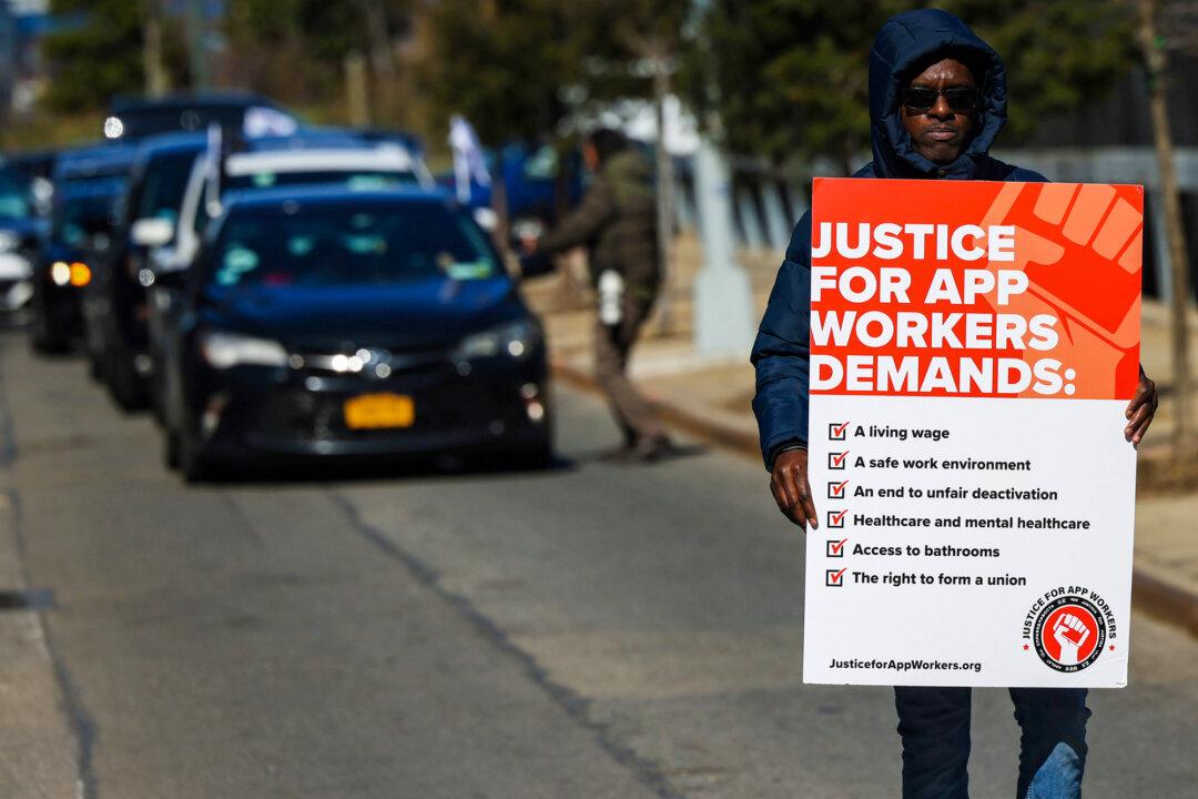 An Uber and Lyft driver carries a sign as he joins other app-based drivers and delivery workers in a protest at the former headquarters of Uber Technologies in New York City on March 29, 2022. The protesters demand fair pay in response to rising gas prices. (Michael M. Santiago/Getty Images)