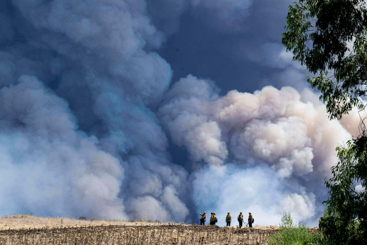 Firefighters monitor the Airport Fire from a ridge near Porter Ranch in Trabuco Canyon, Calif., on Sept. 10, 2024. (Paul Bersebach/The Orange County Register via AP)