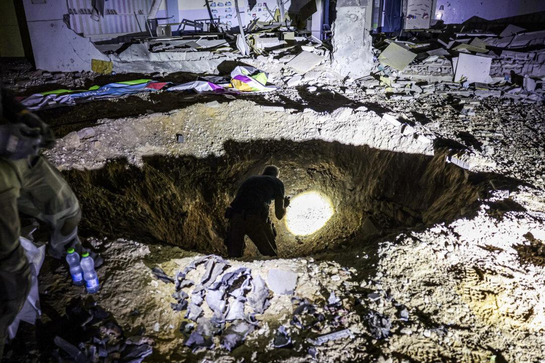 Members of Israel's Home Front Command and police forces inspect a crater left by an exploded projectile at a heavily-damaged school building in Israel's southern city of Gedera on Oct. 1, 202, after Iran fired between 150 and 200 missiles in an attack on Israel. (MENAHEM KAHANA/AFP via Getty Images)