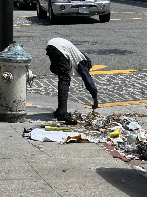 A homeless man picks through trash in San Francisco’s Tenderloin District, on May 16, 2024. (Brad Jones/The Epoch Times)