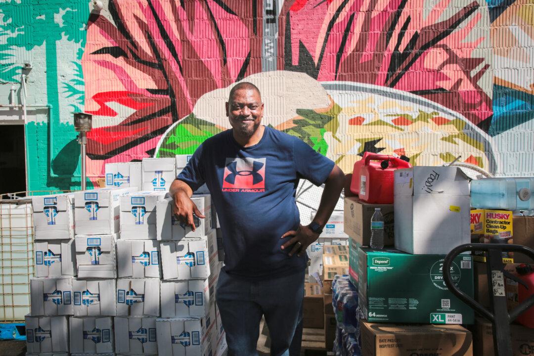 Pastor Micheal Woods of Western Carolina Rescue Ministries leans on a stack of donated drinking water in Asheville, N.C., on Oct. 3, 2024. (Richard Moore/The Epoch Times)