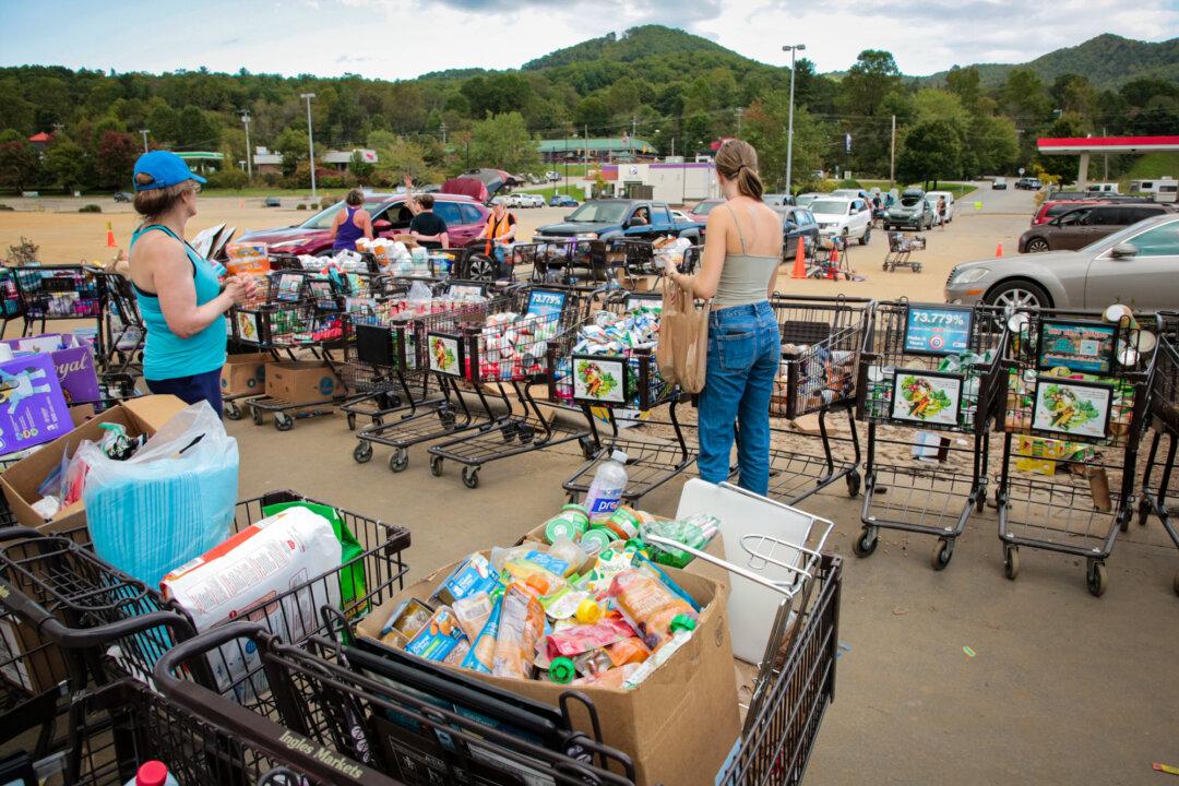 Volunteers hand out food at a drive-thru donation site to flood-affected residents of Swannanoa, N.C., on Oct. 2, 2024. (Richard Moore/The Epoch Times)