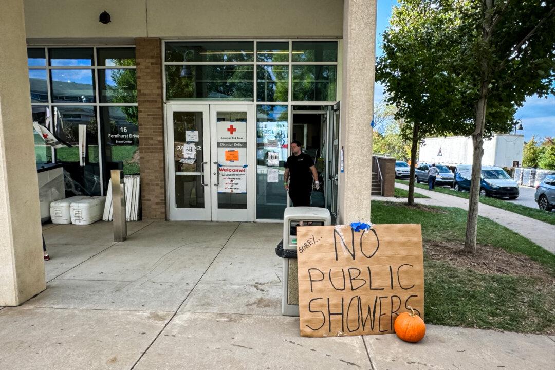 (Top) The remains of a house atop Tunnel Road Bridge in Asheville, N.C., on Oct. 3, 2024. (Bottom) A sign reads “No Public Showers” outside an American Red Cross Relief Shelter in Asheville, N.C., on Oct. 3, 2024. (Arjun Singh/The Epoch Times)