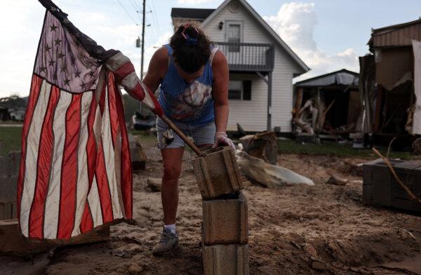 Roxanne Brooks mounts an American flag to a stack of cinder blocks outside her friend's destroyed mobile home (R) in the aftermath of Hurricane Helene flooding in Swannanoa, N.C., on Oct. 6, 2024. (Mario Tama/Getty Images)