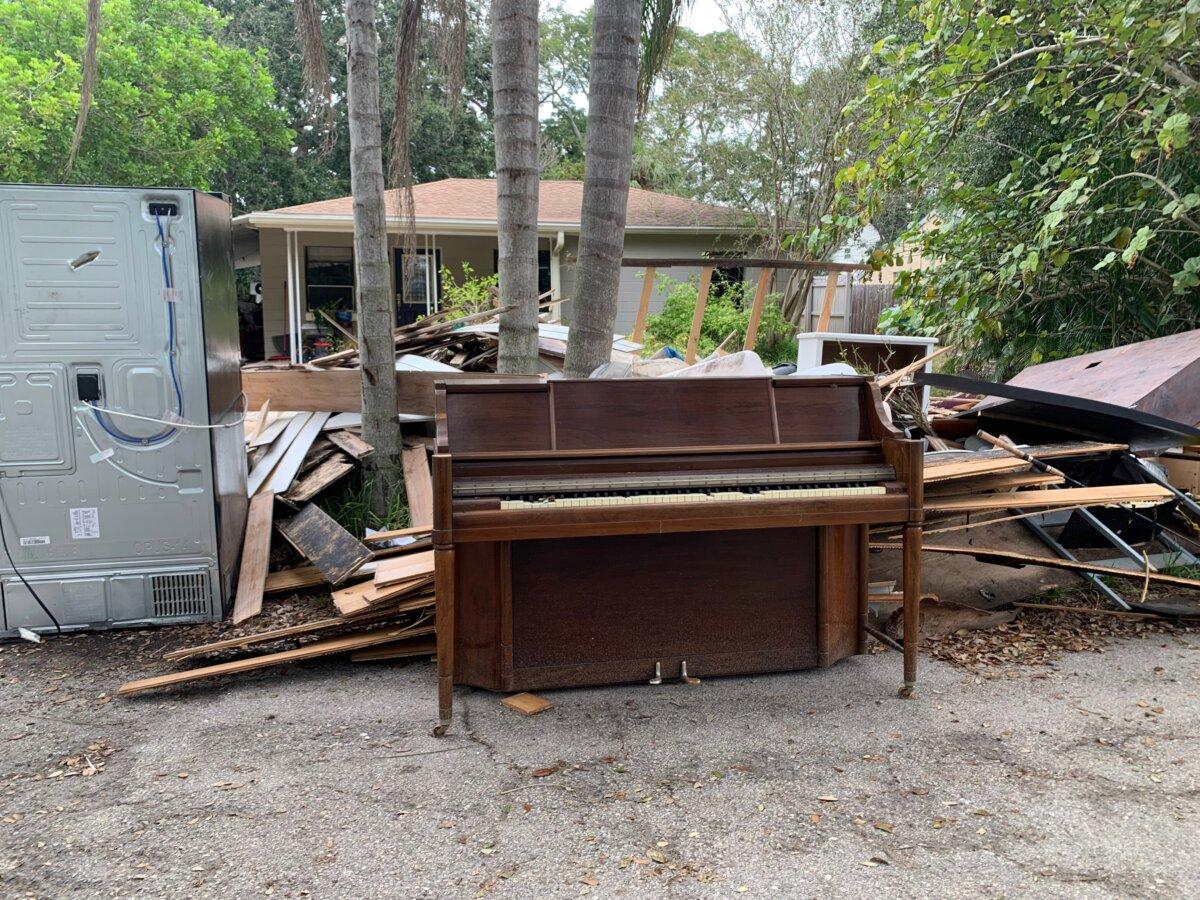 An upright piano stands in a pile of debris from Hurricane Helene outside a home in South Tampa, Fla., on Oct. 8, 2024. (T.J. Muscaro/The Epoch Times).