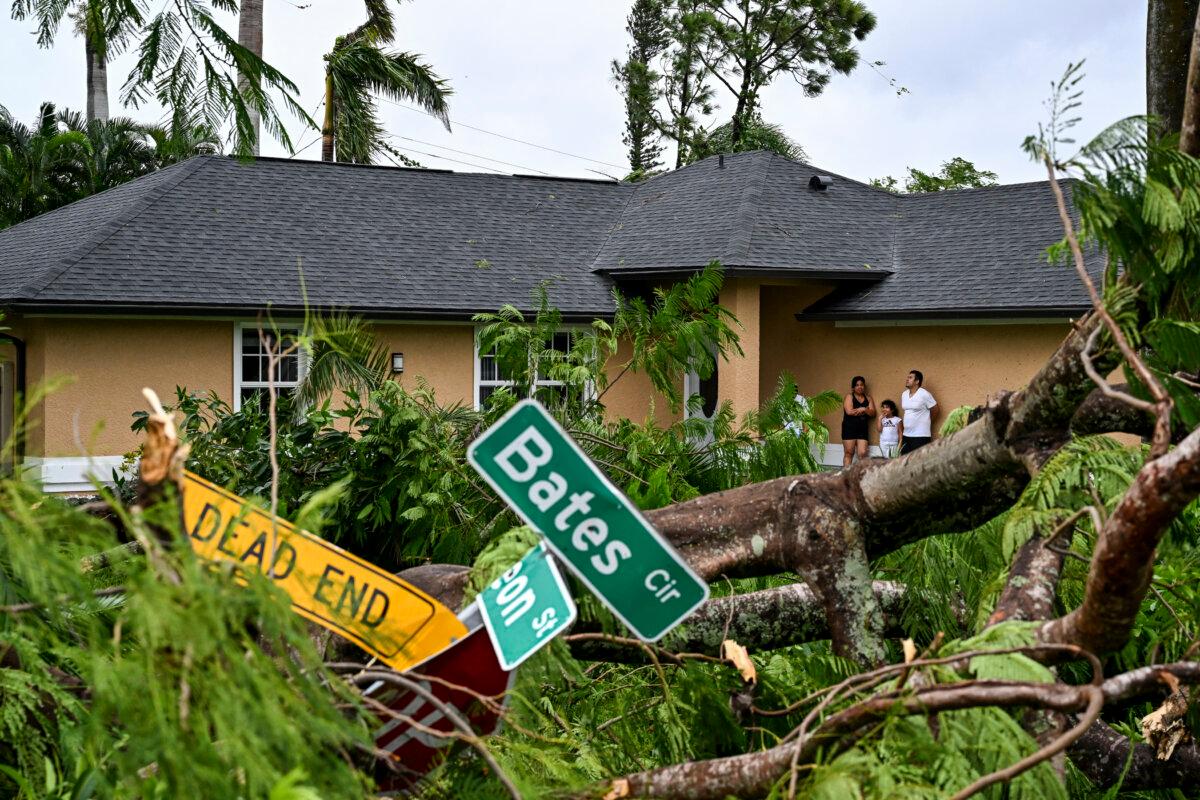 Oscar Garcia (R) with his family stands outside his house after getting hit by a reported tornado in Fort Myers, Fla., on Oct. 9, 2024, as Hurricane Milton approaches. (Chandan Khanna//AFP via Getty Images)