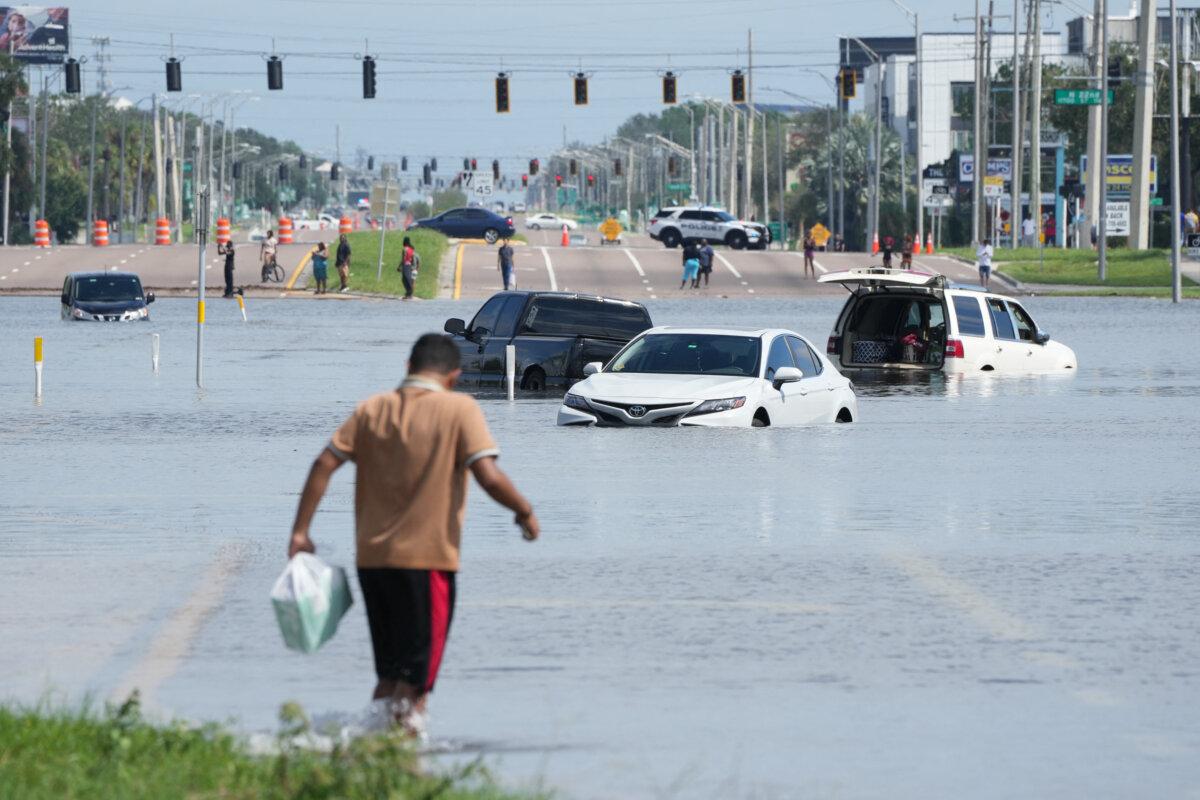 A man walks past vehicles in streets flooded by Hurricane Milton in the southeast Seminole Heights section of Tampa, Fla., on Oct. 10, 2024. (Bryan R. Smith/AFP via Getty Images)