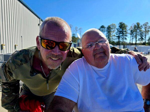 Keith Goodman (R) and Paul Perkins enjoy the good weather outside the Western North Carolina Agricultural Center in Fletcher, N.C., on Oct. 8, 2024. The center is currently housing 220 displaced hurricane survivors. (Allan Stein/The Epoch Times)