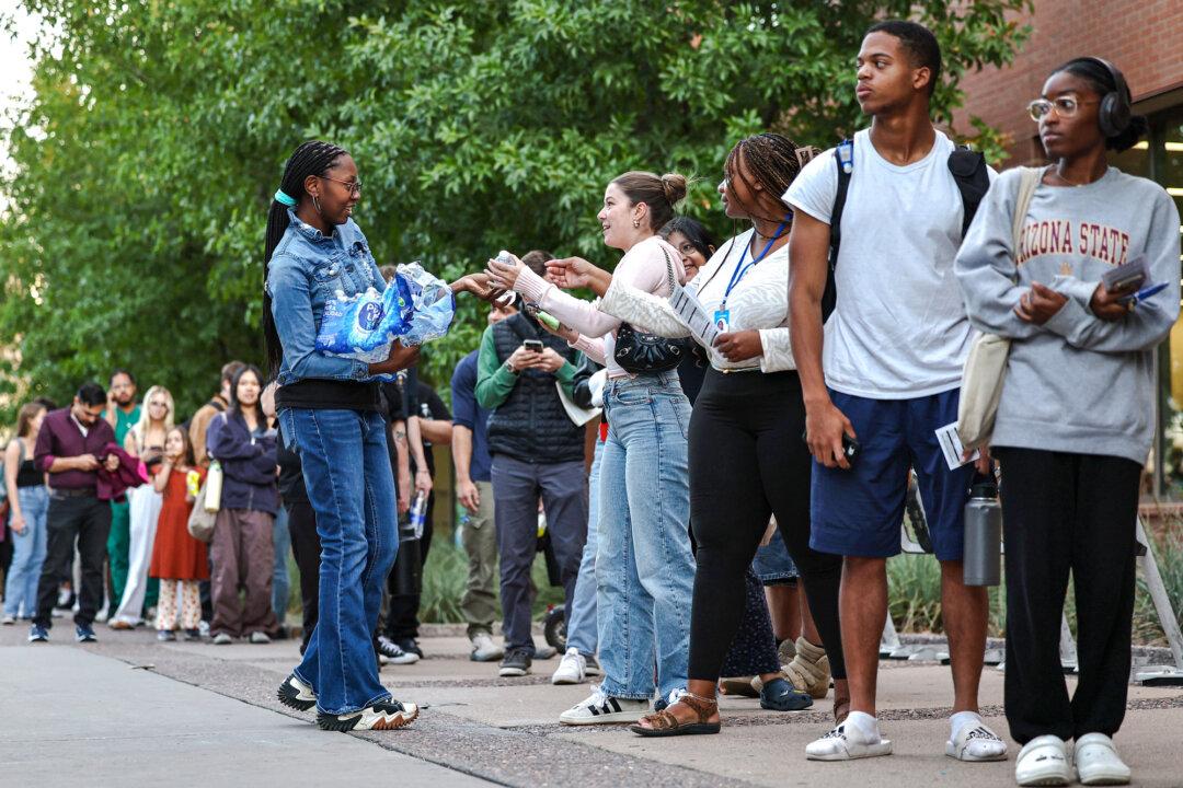 A person passes out water to voters waiting in line before the polls close at Arizona State University in Tempe, Ariz., on Nov. 5, 2024. Young voters made up 15 percent of President-elect Donald Trump's votes. (Mario Tama/Getty Images)