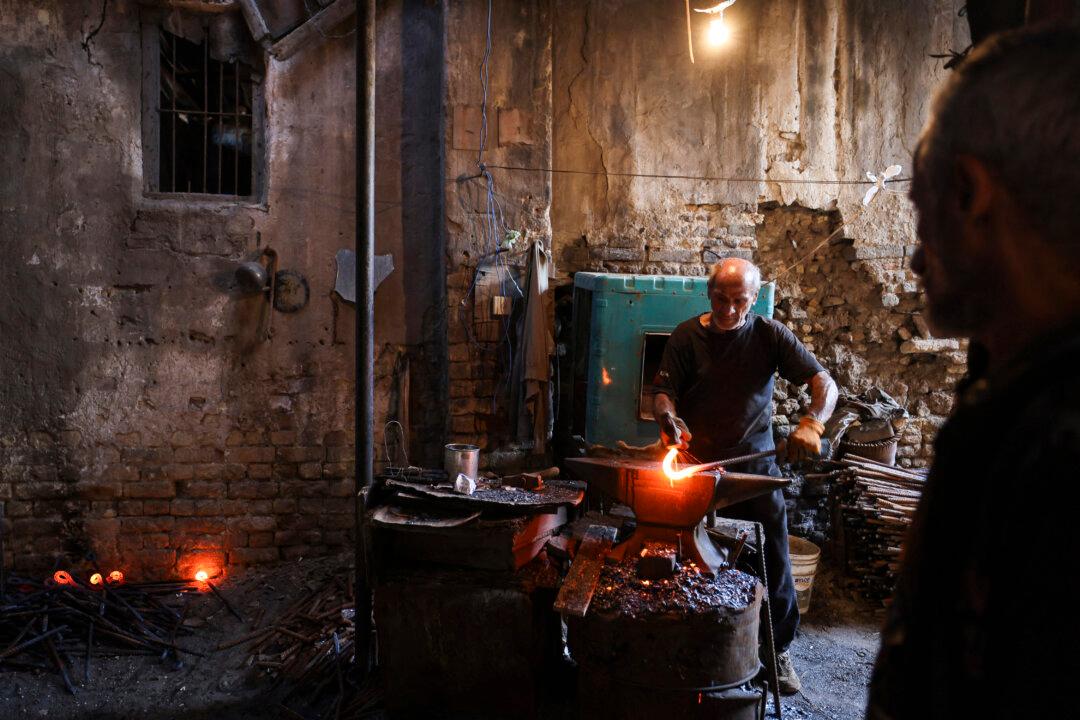 An Iraqi ironsmith hammers molten iron to make tent rods in a workshop in Baghdad, Iraq, on Nov. 14, 2024. (Ahmad Al-Rubaye/AFP via Getty Images)