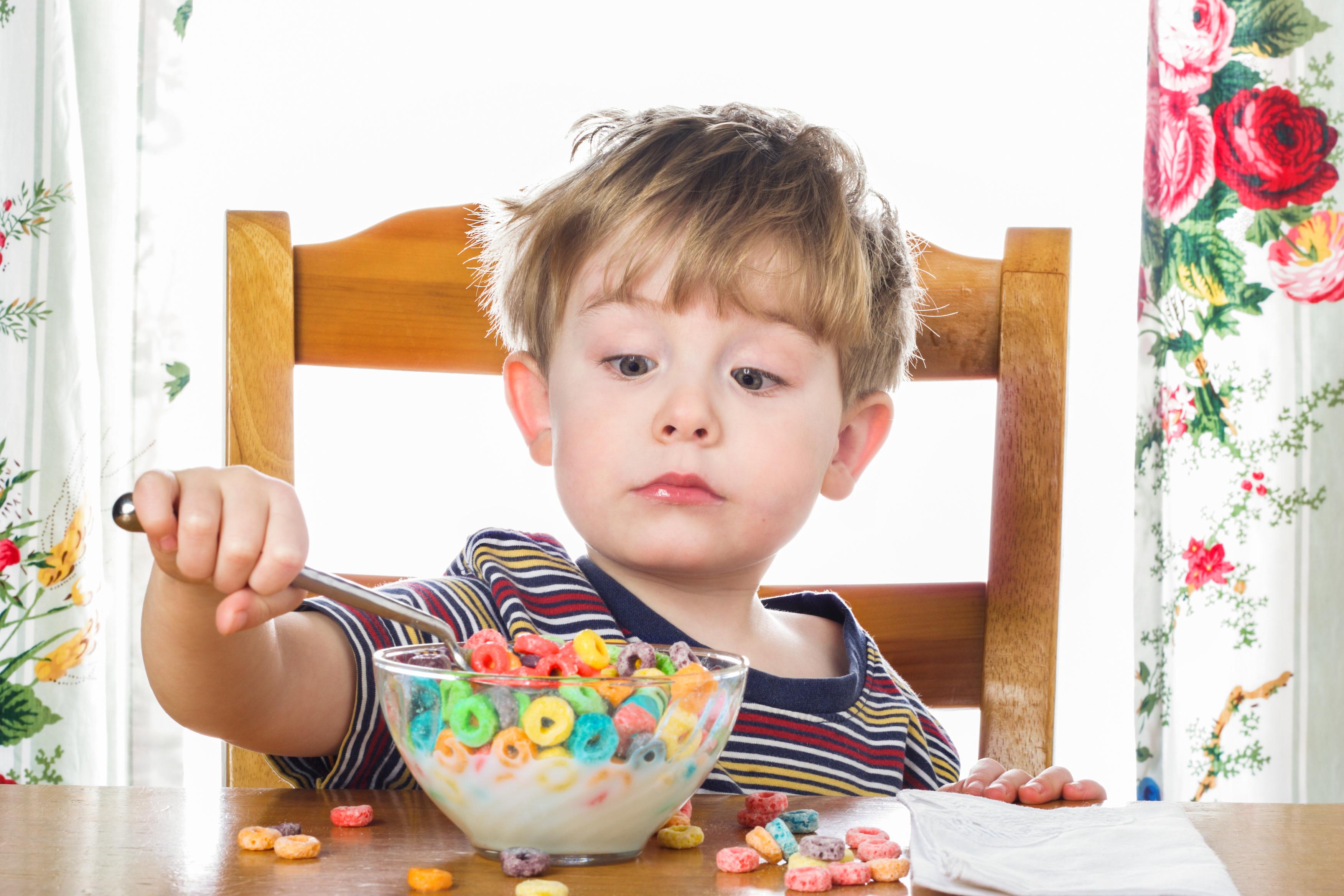 A young boy eats breakfast on his own. (Suzanne Tucker/Shutterstock)