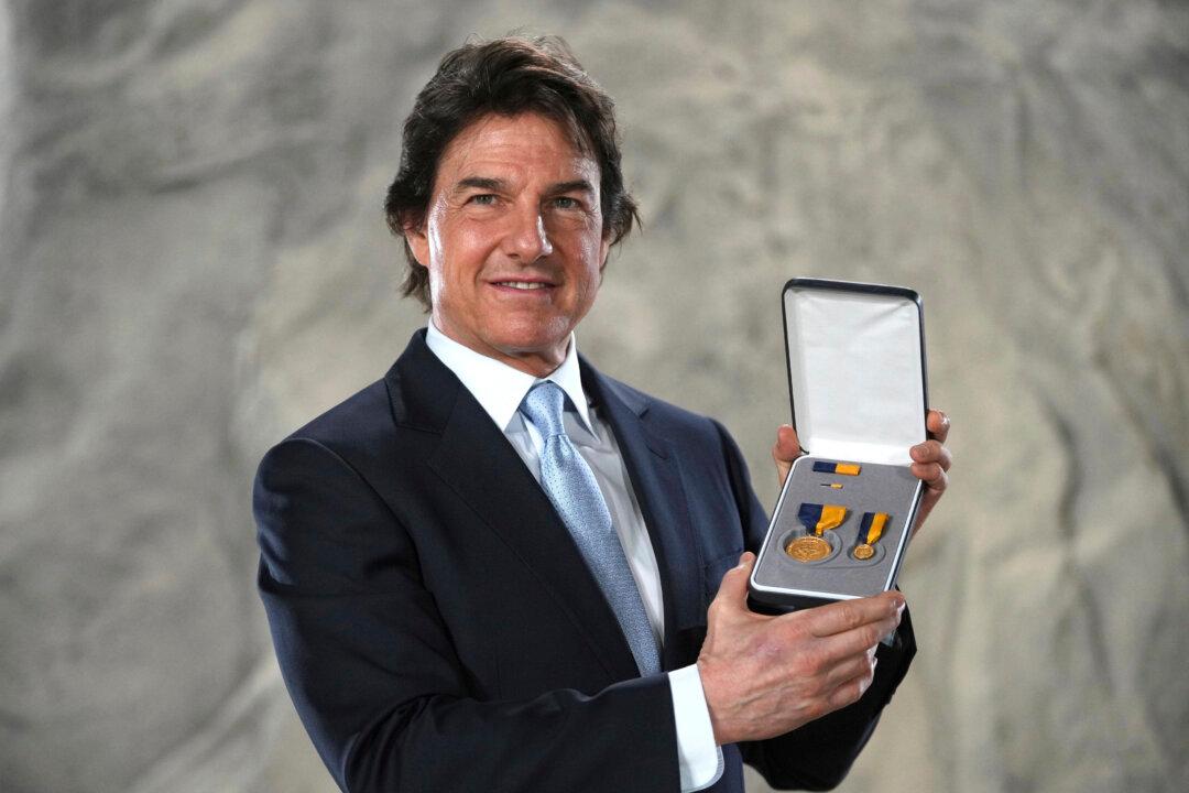 Tom Cruise poses with the Navy Distinguished Public Service Award received from The United States Secretary of the Navy Carlos Del Toro, at the Longcross South Studios, in Runnymede, Surrey, England, on Dec. 17, 2024. (Kin Cheung/AP Photo)