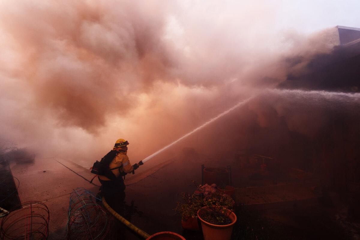 Firefighters work to extinguish flames engulfing a home as a brush fire rages in Pacific Palisades, Calif., on Jan. 7, 2025. (David Swanson/AFP via Getty Images)