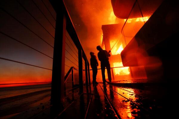 Firefighters work from a deck as the Palisades Fire burns a beachfront property in Malibu, Calif., on Jan. 8, 2025. (Etienne Laurent/AP Photo)