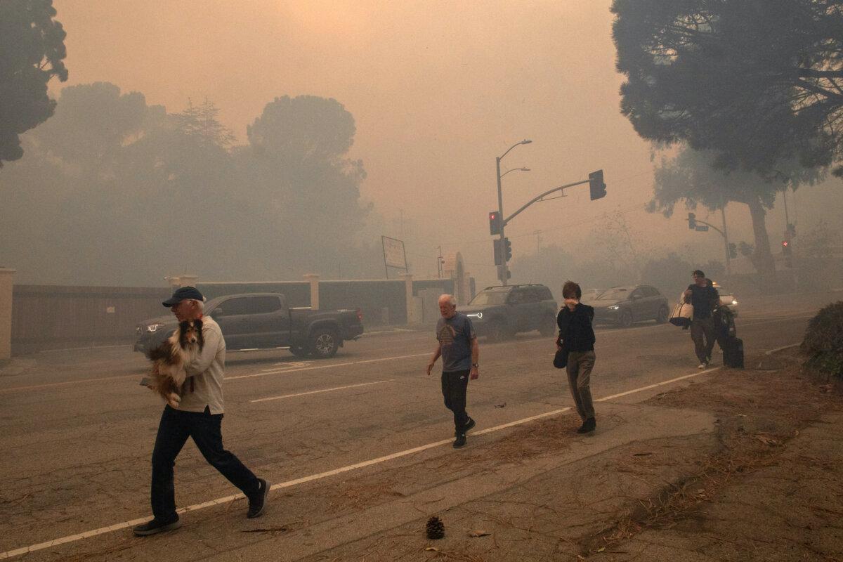 People walk along Sunset Boulevard as they evacuate their homes while the Palisades Fire burns amid a powerful windstorm in Pacific Palisades, Calif., on Jan. 7, 2025. (Apu Gomes/Getty Images)