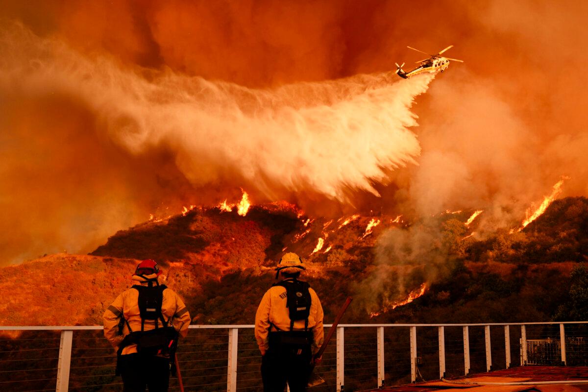 Firefighters watch as water is dropped on the Palisades Fire in Mandeville Canyon in Los Angeles on Jan. 11, 2025. (Jae C. Hong/AP Photo)