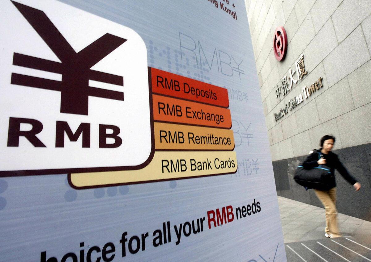 A woman walks past a Chinese "renminbi" (RMB or yuan) currency sign advertising personal services at its headquarters in Hong Kong on Feb. 24, 2004. (Ted Aljibe/AFP via Getty Images)