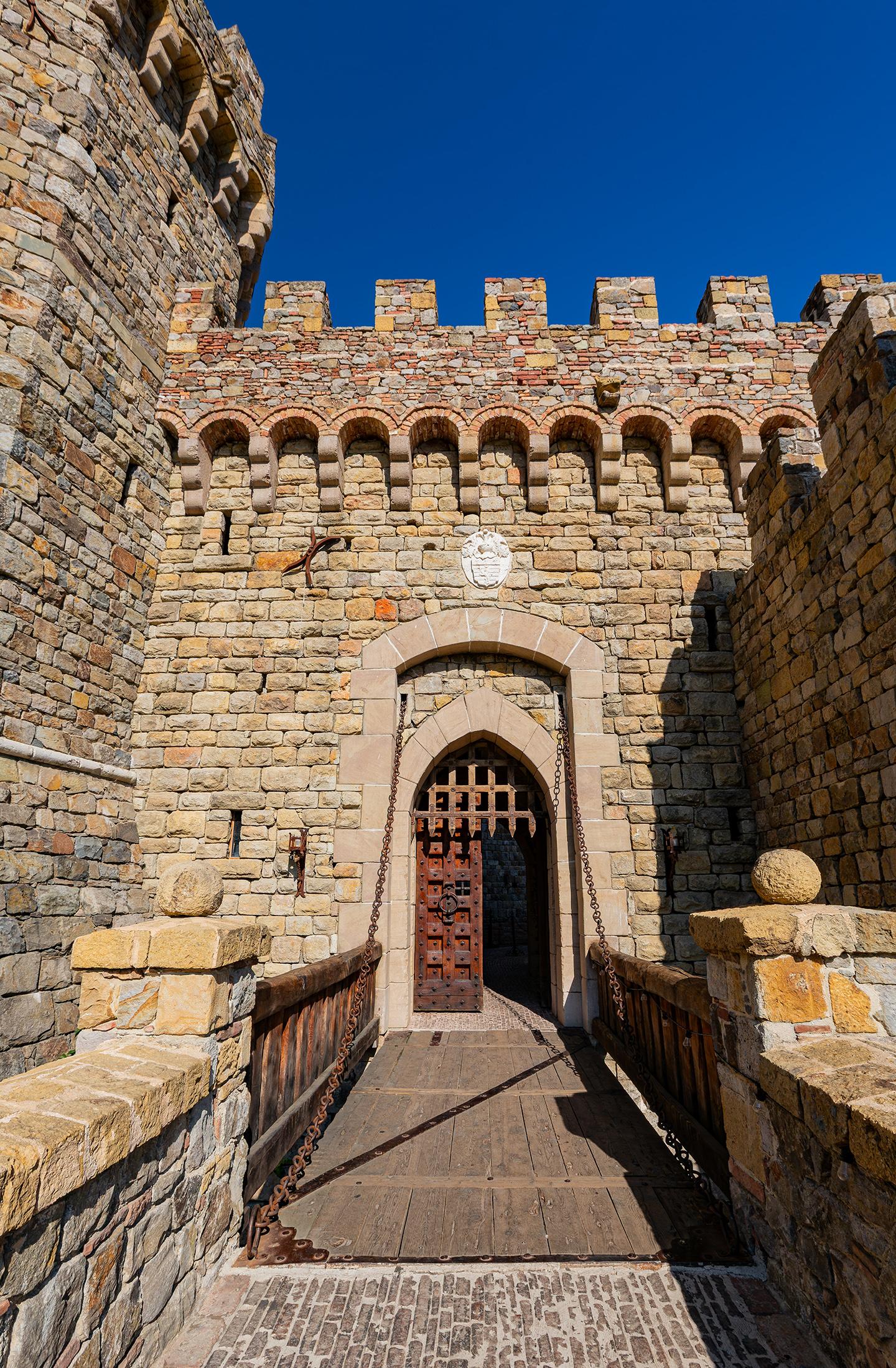 The functioning drawbridge that leads to the castle’s south tower is made of iron, wood, and heavy metals. The stone surrounding the drawbridge was individually chiseled and secured in place to form the walls, railings, and columns. Over the doorway are polished stone blocks that form a segmental or squarish arch, as well as a pointed Gothic arch. A portcullis, or heavy, pointed, metal gate, descends in front of main wooden and iron double doors. (Kit Leong/Shutterstock)