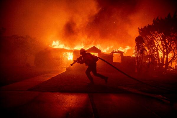 A firefighter battles the Palisades Fire as it burns a structure in the Pacific Palisades neighborhood of Los Angeles on Jan. 7, 2025. (Ethan Swope/AP Photo)
