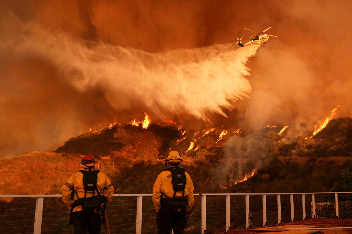 Firefighters watch as water is dropped on the Palisades Fire in Mandeville Canyon in Los Angeles on Jan. 11, 2025. (Jae C. Hong/AP Photo)