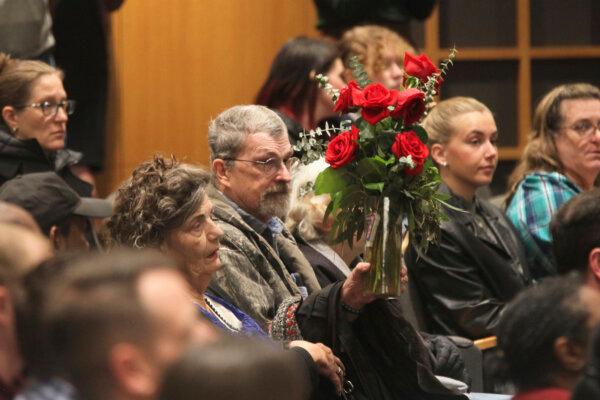 Carla Lee, a retired Wichita State University nursing professor, holds up a vase of red roses to show her support for the families of victims of a deadly collision between a passenger airliner and an Army helicopter, during a prayer vigil in Wichita, Kan., on Jan. 30, 2025. (John Hanna/(AP Photo)