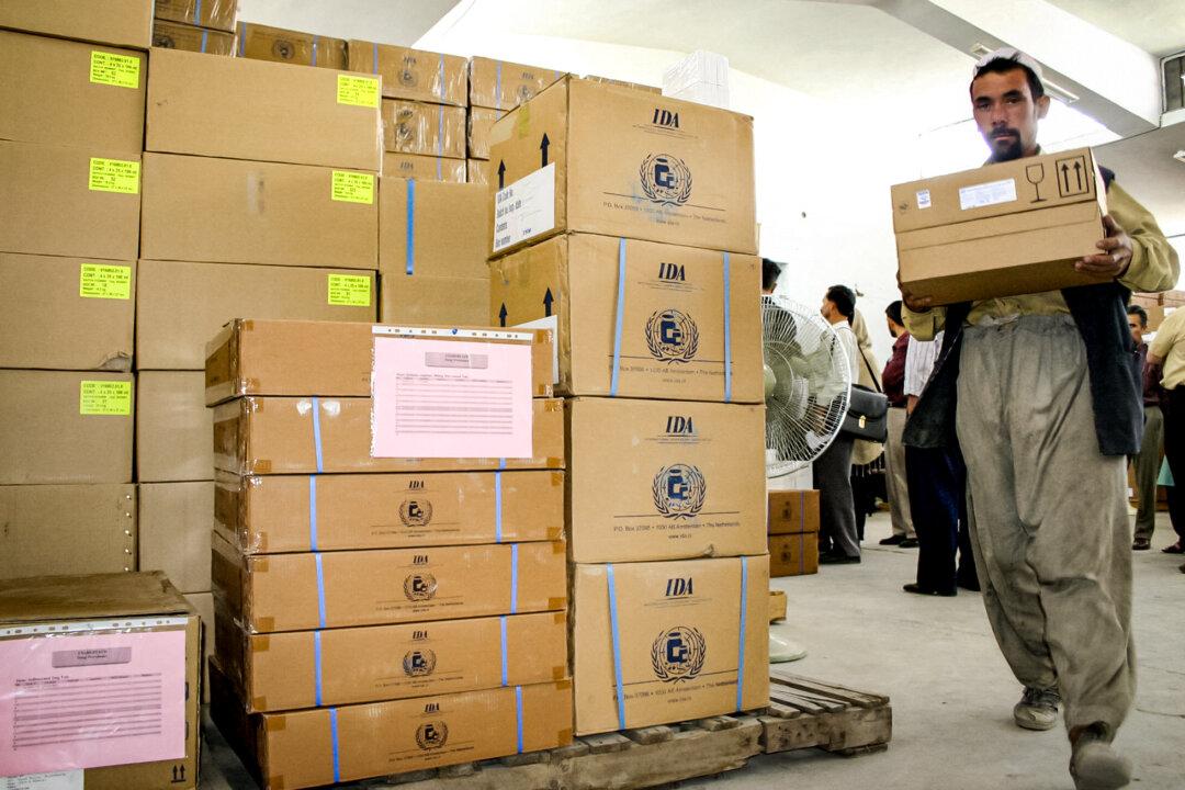 A worker carries a box of medicine donated by USAID, in Kabul, Afghanistan, on June 17, 2004. (Mariam Kosha/AFP via Getty Images)